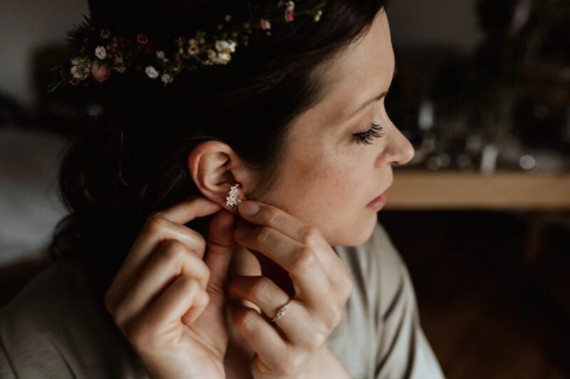 Braut setzt ihre Brautohrringe während der Hochzeitsvorbereitungen ein