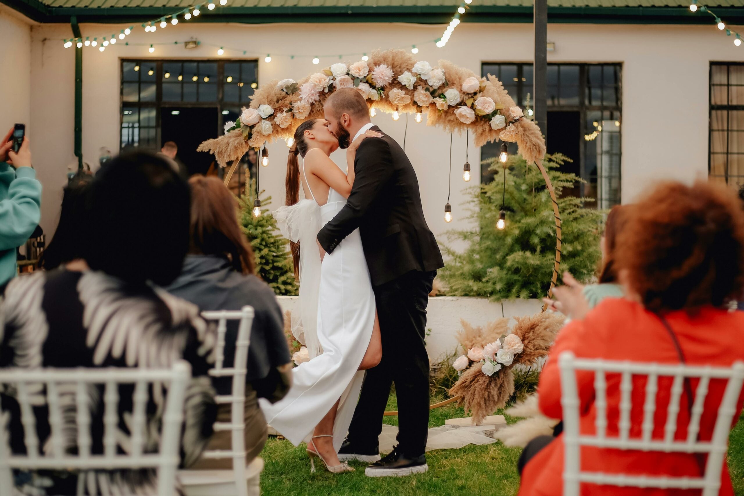 Bride and groom kissing at an outdoor wedding ceremony at home
