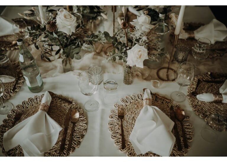 Rustikal gedeckte Hochzeitstafel mit geflochtenen Platzsets und Blumen