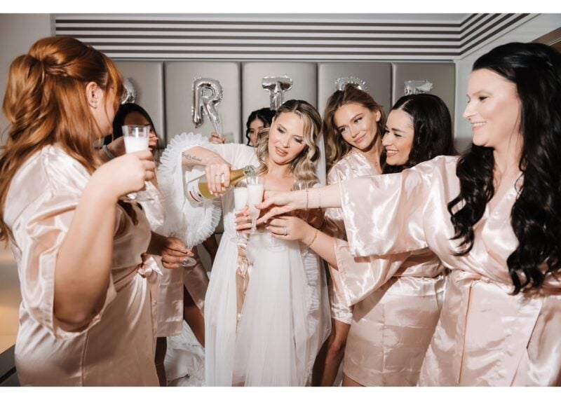 Braut und Brautjungfern stoßen beim Getting Ready mit Sekt auf den Hochzeitstag an