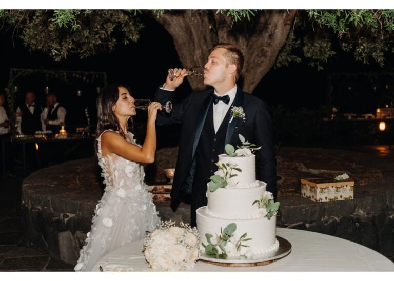 Braut und Bräutigam stoßen mit Champagner vor ihrer Hochzeitstorte bei der Hochzeitsfeier an