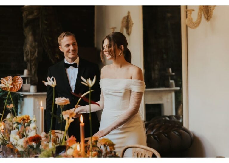 Braut und Bräutigam stehen neben einer festlich gedeckten Hochzeitstafel im Innenraum