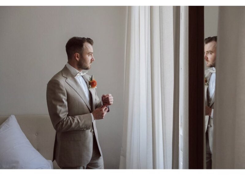 Bräutigam richtet seine Manschette und blickt vor der Hochzeit aus dem Fenster