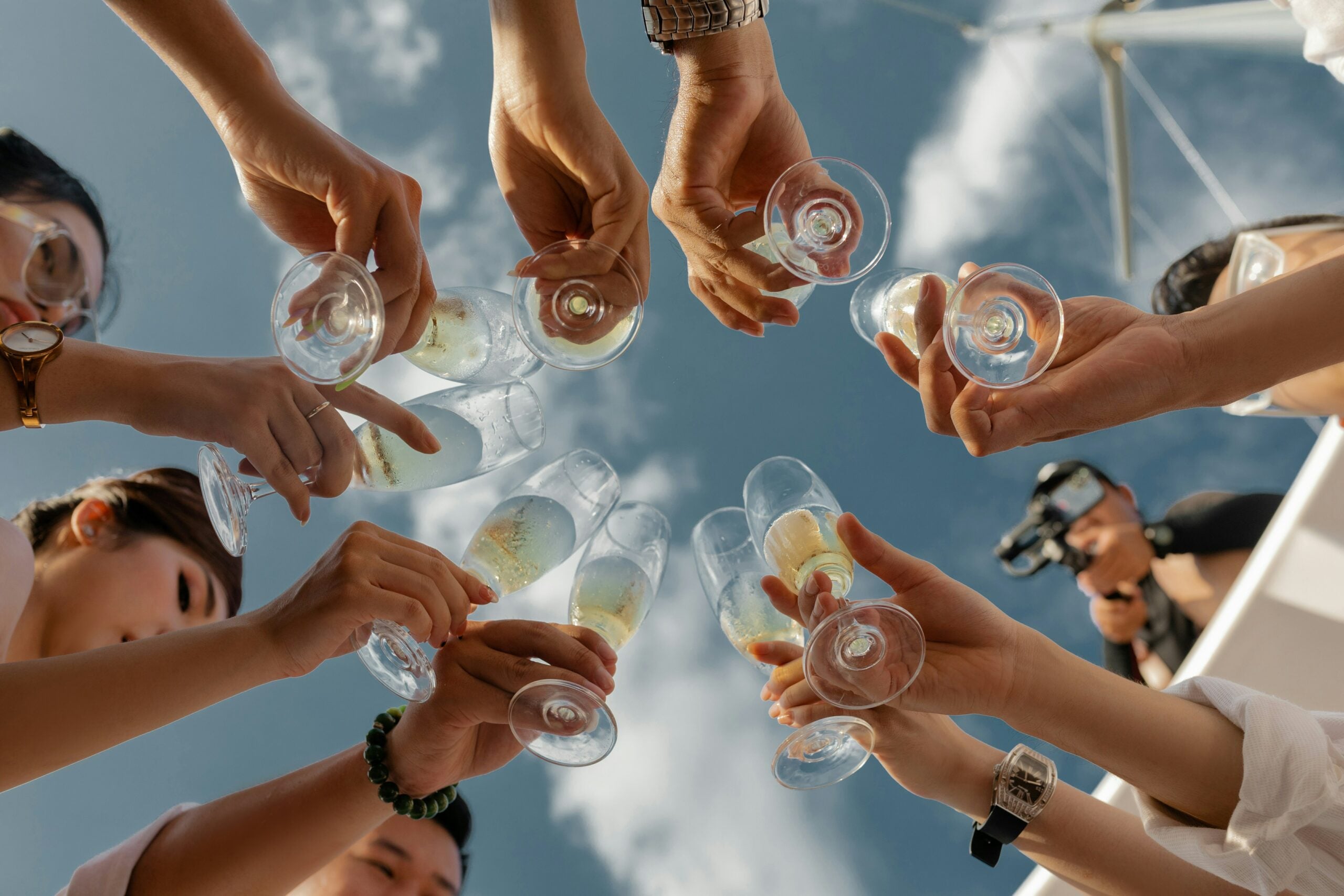 a group of hens toasting with champagne on a hen do under a blue sky