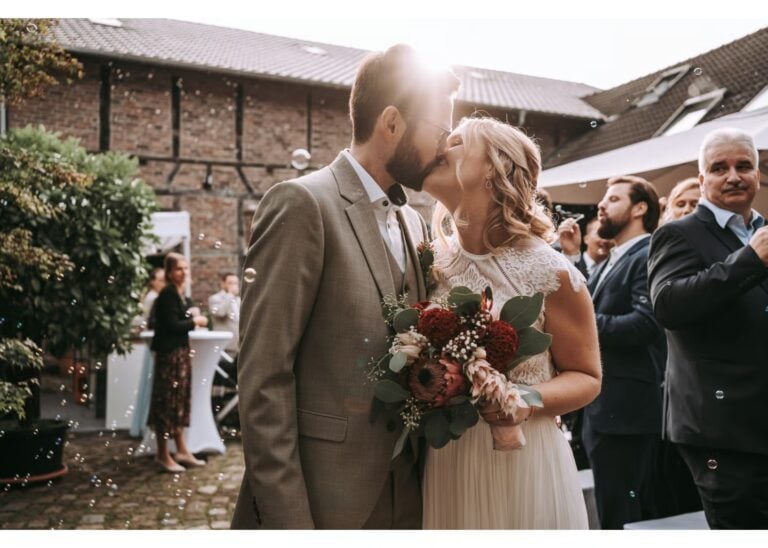 Braut und Bräutigam küssen sich nach der Trauung vor den Hochzeitsgästen
