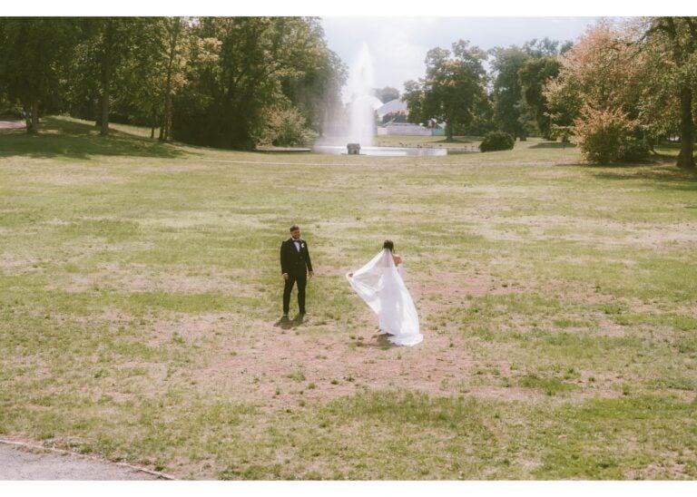 Braut läuft mit wehender Schleppe über eine Wiese auf den Bräutigam zu