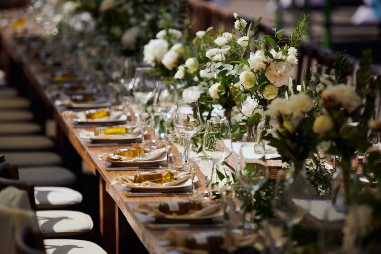 Lange Hochzeitstafel mit eleganter Blumendekoration, Kerzen und stilvoll eingedeckten Plätzen