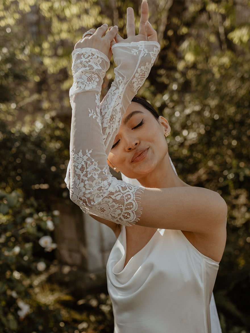 Bride holding her arms up showing her lace fingerless wedding gloves