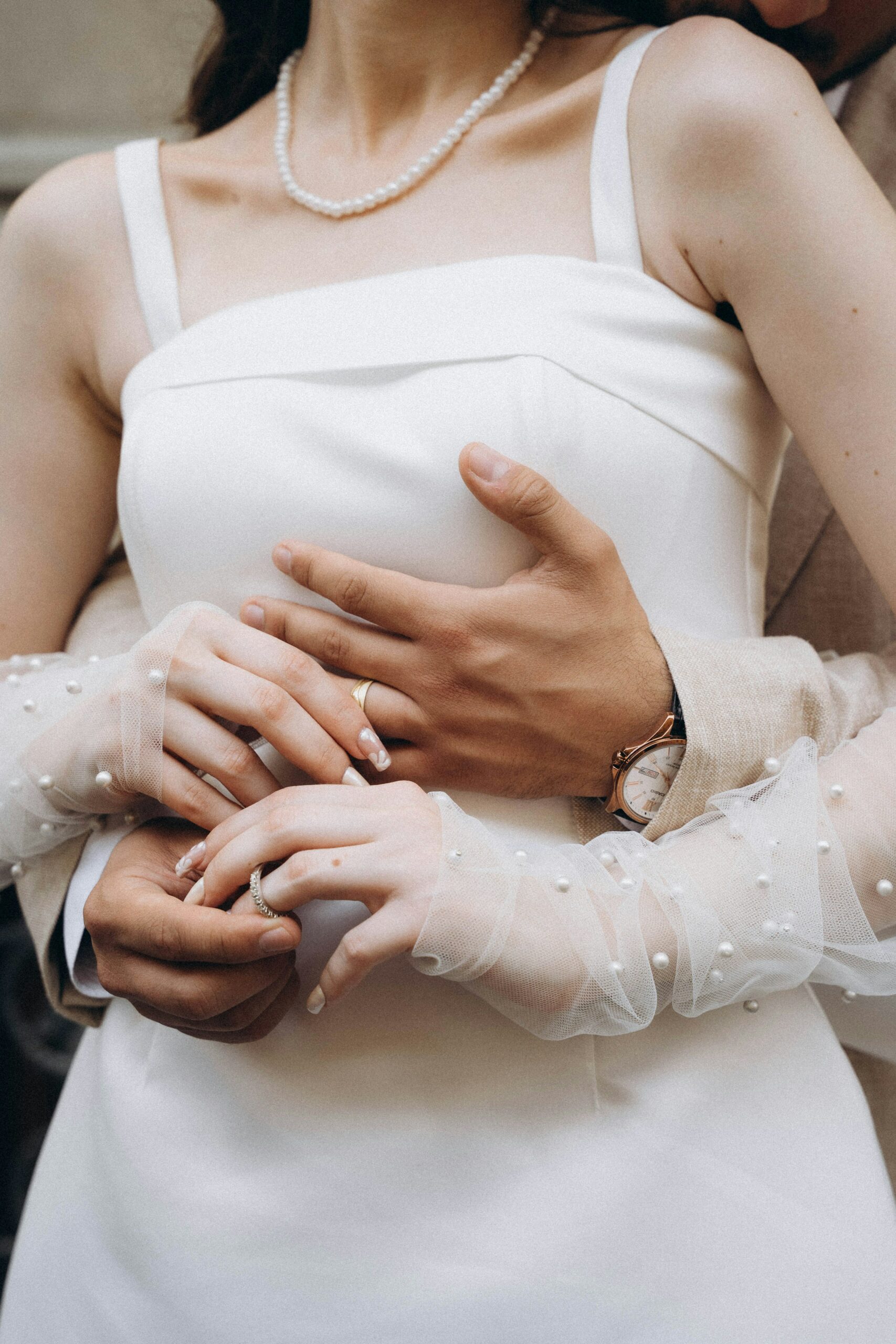 Bride wearing pearl-studded tulle gloves with a satin wedding dress