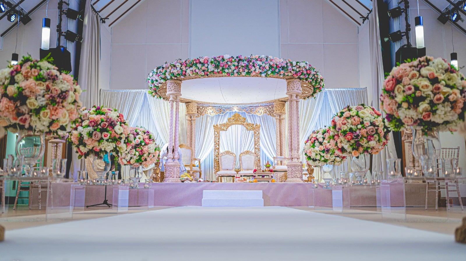 a mandap covered with beautiful flowers and a flower-lined aisle