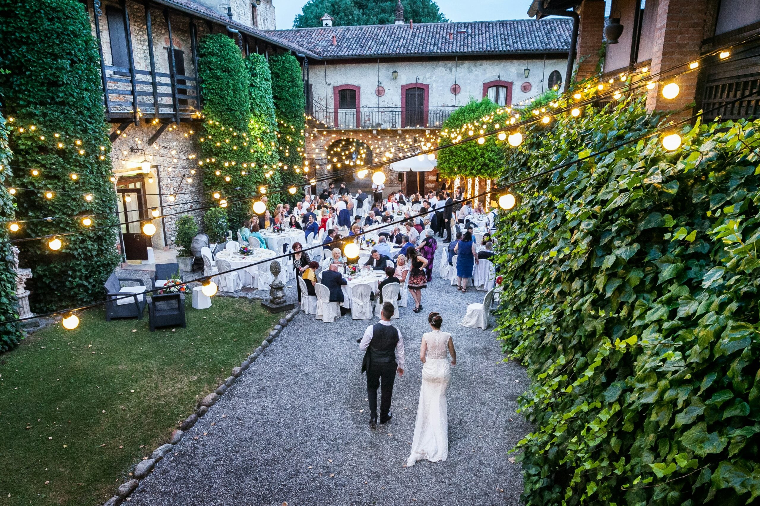 A bride and groom approach an outdoor wedding reception hand in hand