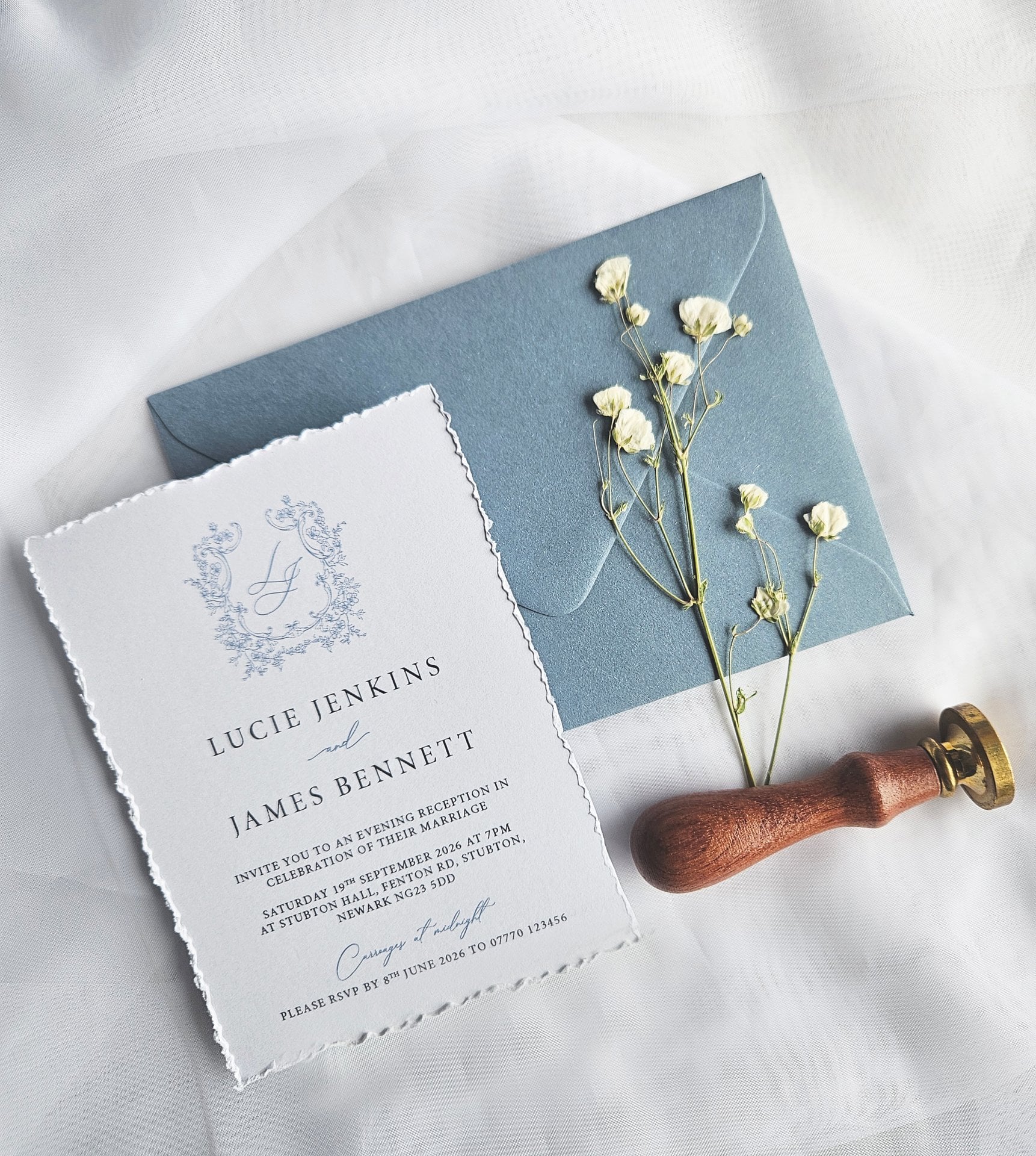 a traditional paper wedding invitation with hand-torn edges and a powder blue envelope