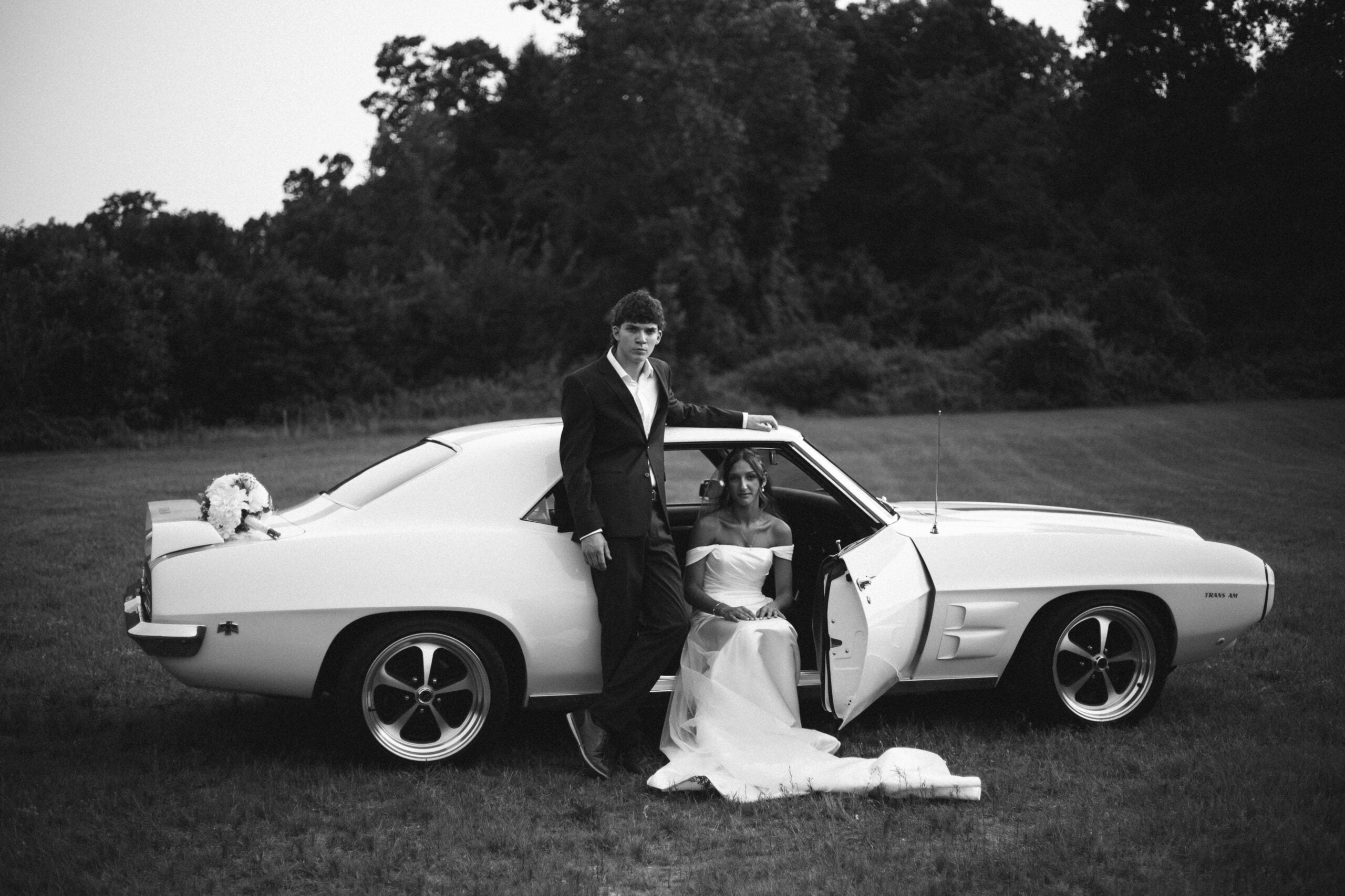 Bride and groom posing with a retro wedding sports car