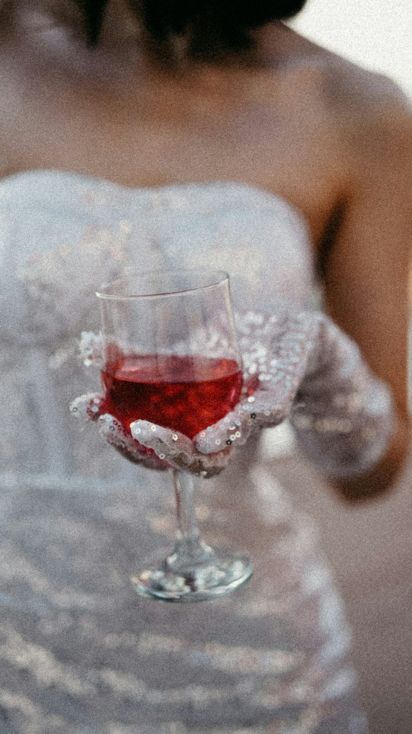 Bride holding a glass of rose wine wearing white sparkly wedding gloves