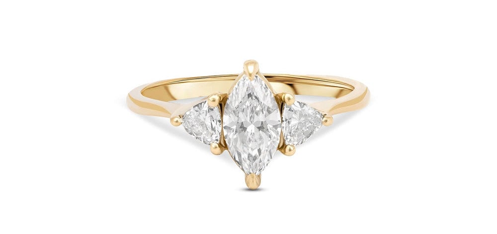 a yellow gold engagement ring featuring a marquise cut diamond in the centre and two smaller diamonds either side