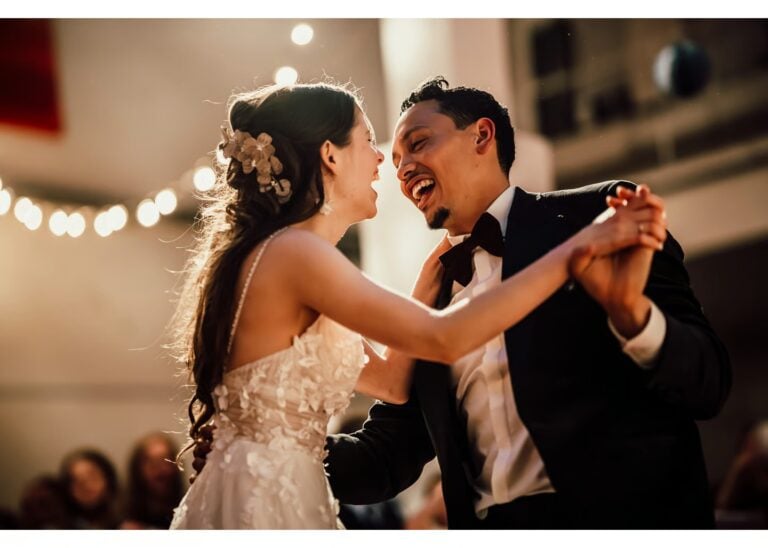 Brautpaar tanzt lachend bei der Hochzeitsfeier unter Lichterketten