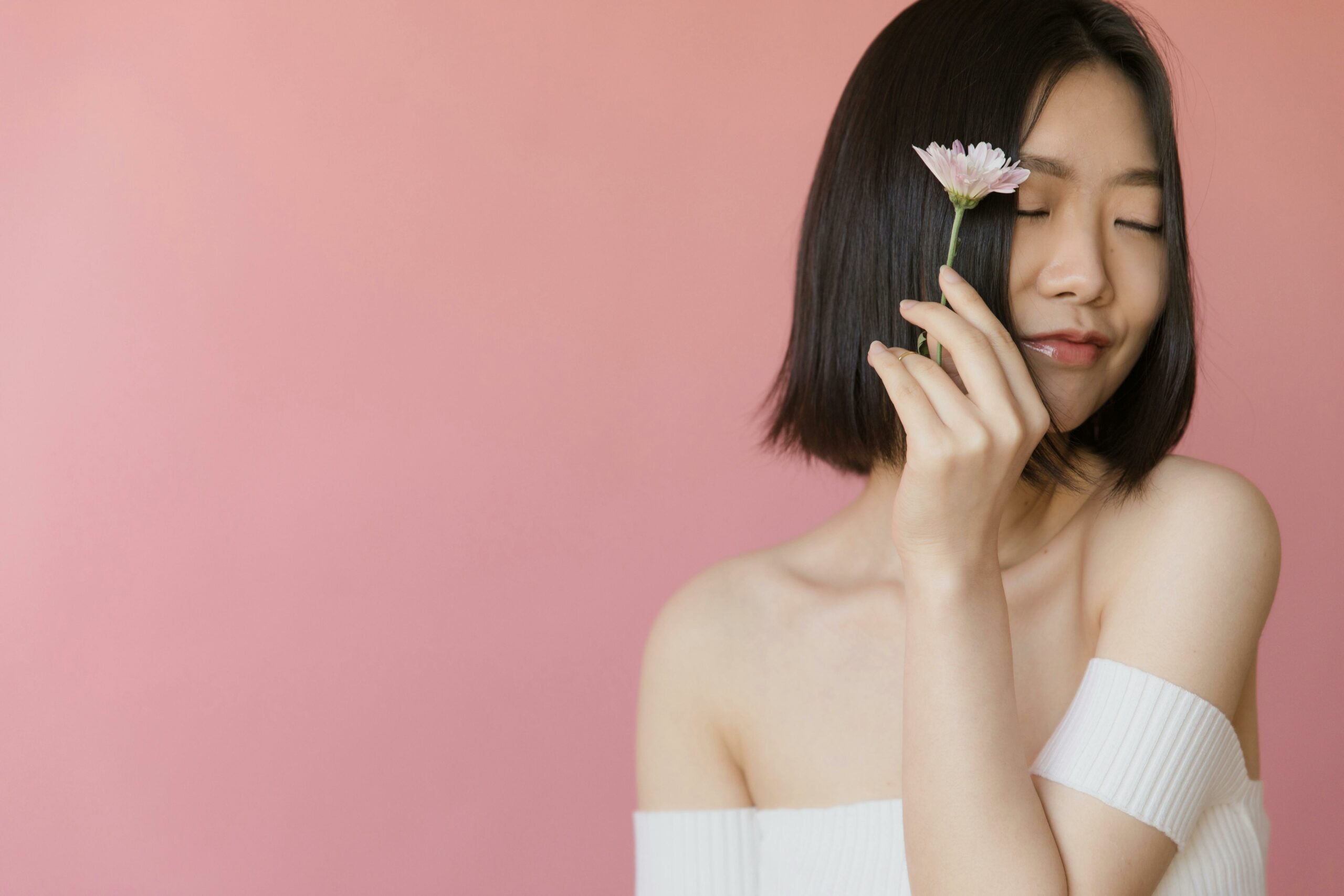 Asian woman with sleek bob against pink backdrop