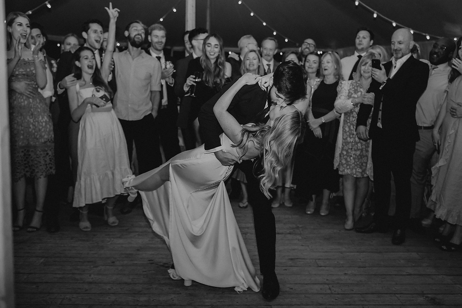 a bride and groom embracing on the dancefloor as guests look on and clap