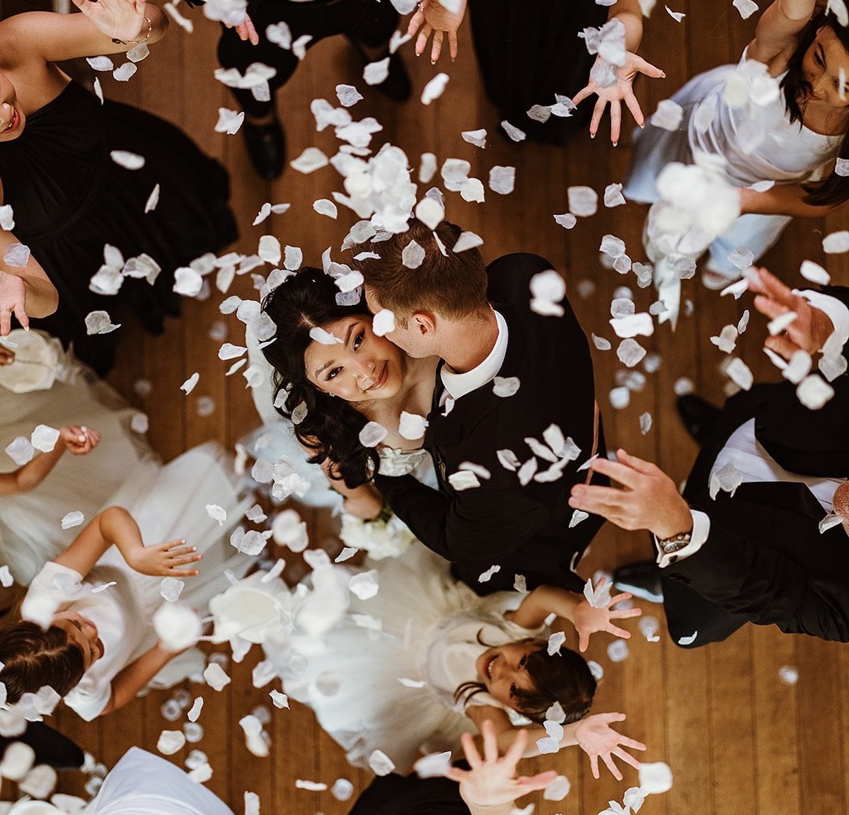 a bride looks up and smiles as she dances her first dance with her groom and guests throw white confetti