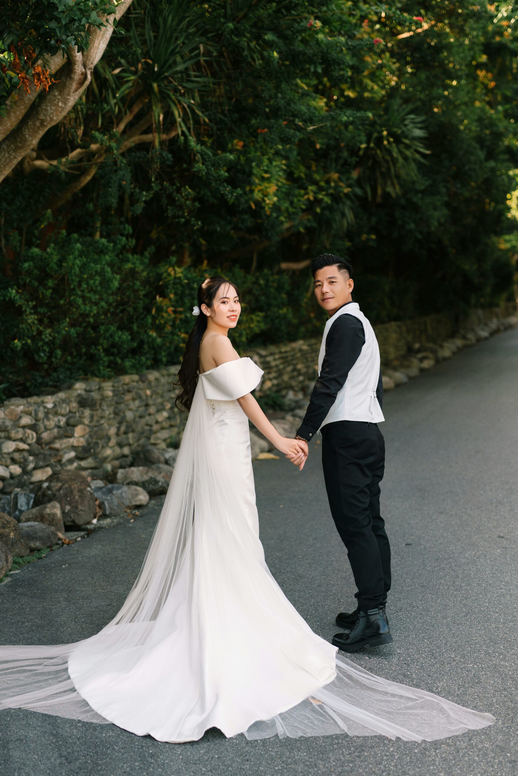 Bride and groom posing hand in hand and looking back towards the camera