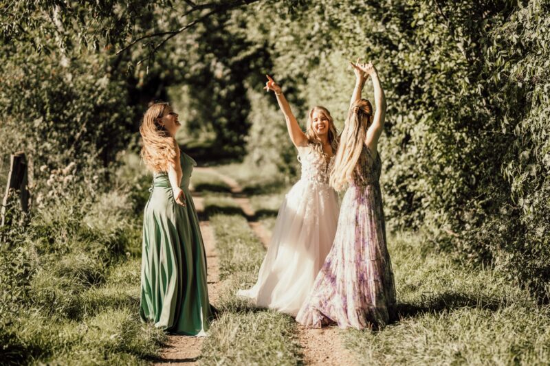 Braut und Freundinnen tanzen fröhlich bei einer Sommerhochzeit