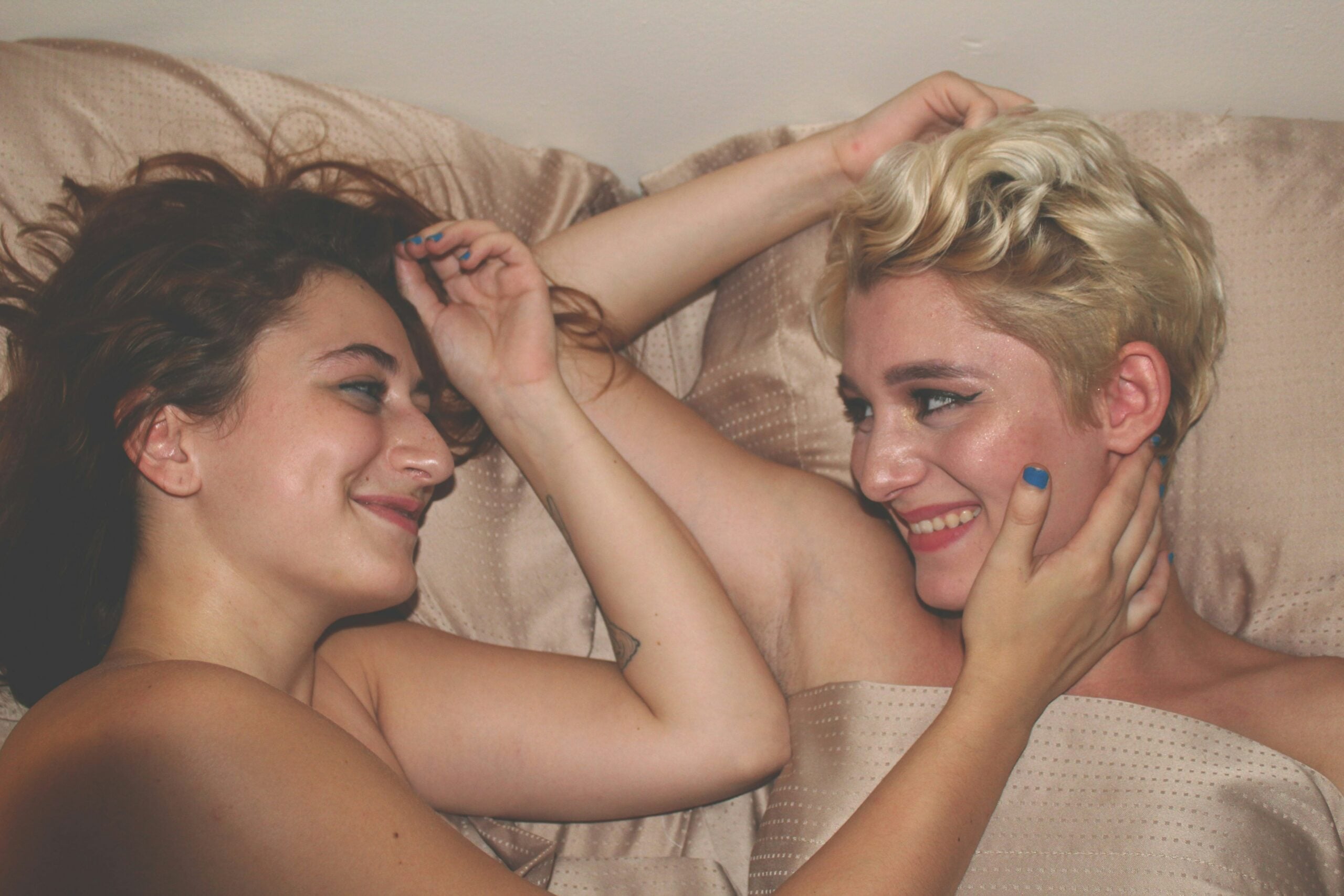 Same sex lgbtq+ couple smiling in bed together