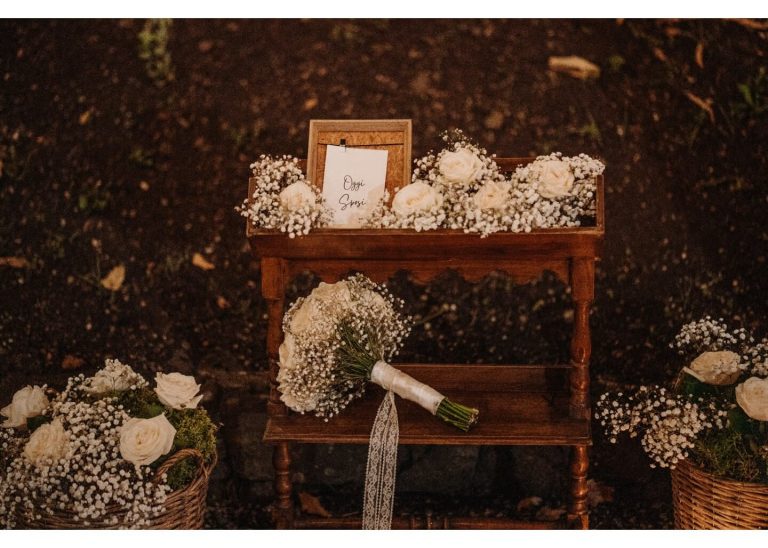 Rustikale Hochzeitsdekoration mit weißen Blumen und Brautstrauß auf Holztisch